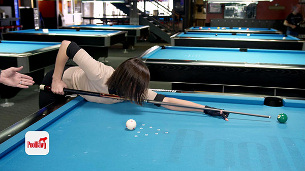 Valerie takes a long shot, with a grip near the end of the cue