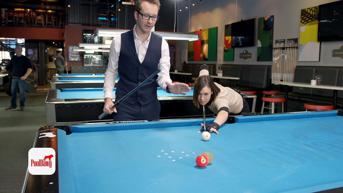 Valerie aims her shot, shooting to replace the “ghost ball” with the cue ball and cut the three ball into the corner pocket.